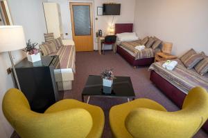 a hotel room with two yellow chairs and a living room at Hotel Junior Poděbrady in Poděbrady