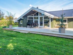 a green house with a deck and a house at 8 person holiday home in Sydals-By Traum in Skovmose
