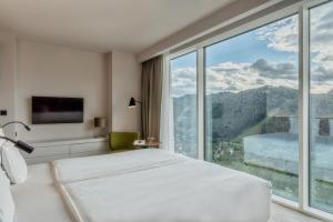 a bedroom with a bed and a large window at Hotel Pieniny Grand Wellness & SPA - Destigo Hotels in Szczawnica