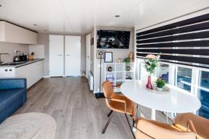a kitchen and a living room with a table and chairs at Floating holiday home close to AMS in Loenersloot