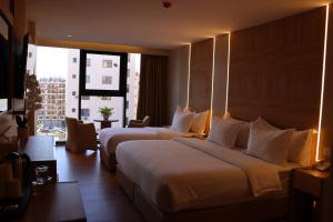 Dos camas en una habitación de hotel con una gran ventana. en Aysel Hotel, en Áqaba