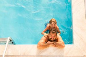 un hombre con un niño en los hombros en una piscina en EVEN Hotel Miami - Doral Area by IHG, en Sweetwater