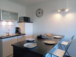 a kitchen with a table with plates and wine glasses at studio à 100m de la plage et de la piscine in Cervione
