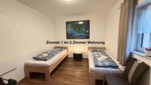 two beds in a room with a picture on the wall at Kim Homestay B Zimmer B1 in Sömmerda