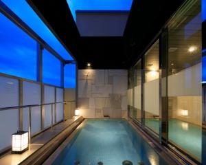an indoor swimming pool in a building with windows at Candeo Hotels Kobe Tor Road in Kobe
