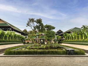 a garden with a fountain in front of a building at Grand Mercure Khao Lak Bangsak in Khao Lak