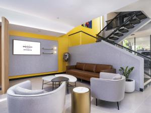 Un vestíbulo con un sofá, una mesa y sillas. en Mercure Rockhampton, en Rockhampton