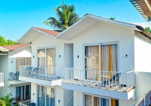 une maison avec des balcons et un palmier en arrière-plan dans l'établissement Beach walk resort by tvessa-100m to beach, à Mandrem