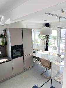 a kitchen with white cabinets and a glass table at Luxury apartment Black Pearl Beluga with private Pool and Jacuzzi in Novalja +68 photos