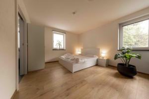 Staudach-EgerndachにあるFerienwohnung Siebenschläferの白いベッドと鉢植えの植物が備わるベッドルーム1室