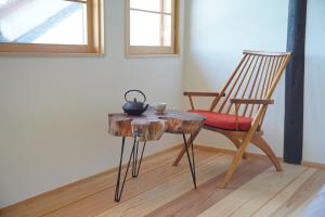 a wooden table with a chair and a table with a cup on it at Yugashira Kuu ゆがしら空 in Imabari