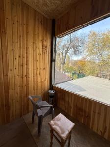 een kleine kamer met een stoel en een raam bij TaTa Guest House in Bisjkek