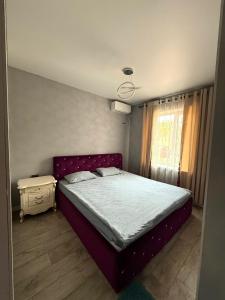 een slaapkamer met een paars bed en een raam bij TaTa Guest House in Bisjkek