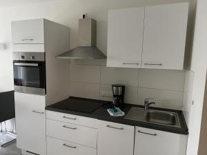 Una cocina con gabinetes blancos y un fregadero. en Ferienwohnung L254 an der Ostsee, en Brasilien