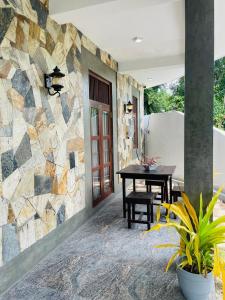a patio with a table and a stone wall at Bosilu Villa in Weligama