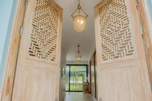 Un pasillo con puertas de madera y una lámpara de araña. en 4BR Laguna Golf View Pool Villa Retreats Phuket, en Laguna Phuket