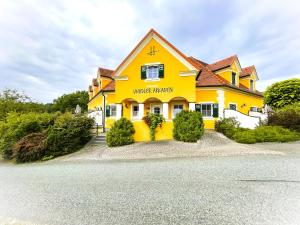 a yellow house on a gravel road at Ferienhof Uhudler-Arkaden in Stegersbach