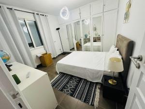 a white bedroom with a bed and a mirror at Sea View Appartement a la Marsa plage in Douar el Hafey