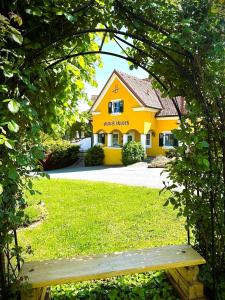 a wooden bench in front of a yellow house at Ferienhof Uhudler-Arkaden in Stegersbach