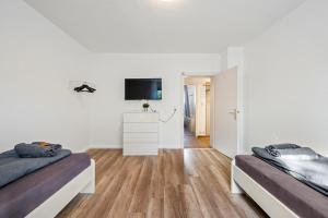 a white room with two beds and a tv at BIR02 Wohnung mit Garten in Rüsselsheim! in Rüsselsheim +4 photos