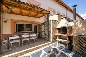 eine Terrasse mit einem Tisch, Stühlen und einem Grill in der Unterkunft Bonita casa en Torrejón del Rey in Torrejón del Rey