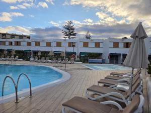 Una piscina de hotel con tumbonas y sombrilla. en Las Brisas Canary Home Rent, en San Bartolomé