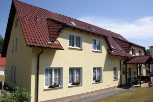 una casa amarilla con techo rojo en Pension Edelstein, en Ostseebad Sellin