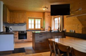 a kitchen with a large wooden table with chairs at Hirschberghütte in Bizau