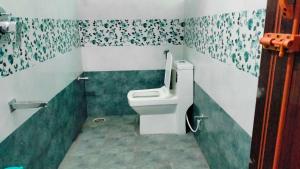 La salle de bains est pourvue de toilettes avec du papier peint vert et blanc. dans l'établissement Hotel O Rajdhani, à Mangalore