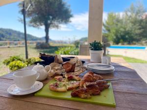 マントンにあるVilla-Monti 5 Star Superhost, Luxury Villa with pool, sleeps 7の木製のテーブルの上に置かれたコーヒーとペストリーの入った皿