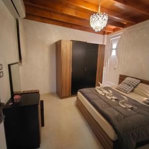 a bedroom with a large bed and a chandelier at Queen of the Nile in Luxor