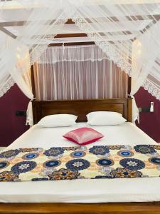 a bed with a red pillow on top of it at Bosilu Villa in Weligama