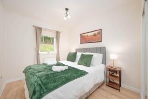 Un dormitorio con una cama grande con una manta verde. en Aberdeen 2BR Flat Near Airport & City Centre, en Aberdeen