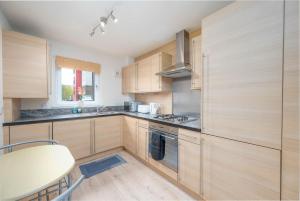 Una cocina con gabinetes de madera y una mesa en ella. en Aberdeen 2BR Flat Near Airport & City Centre, en Aberdeen