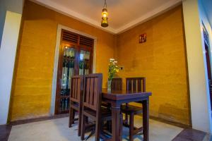 a dining room table and chairs with a yellow wall at Saku Residence in Unawatuna