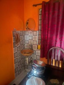 a small bathroom with a sink and a red curtain at Sebastian Homes in Madikeri