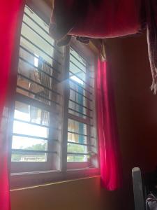 a window with a red curtain in a room at Sebastian Homes in Madikeri