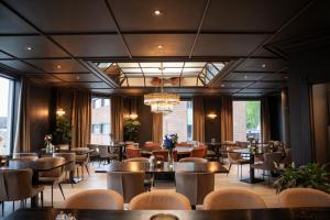ein Restaurant mit Tischen und Stühlen und Fenstern in der Unterkunft Home Hotel Grand Gjøvik in Gjøvik