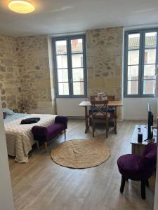 une chambre avec un lit, une table et des chaises dans l'établissement Studio cosy en pierre au cœur du vieux Langon, à Langon