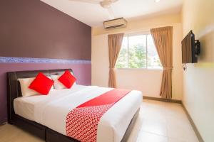 a bedroom with a bed with red pillows and a window at Hotel O Batu Ferringhi Beach formerly ESQ Ferringhi in Batu Ferringhi