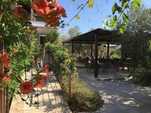 un patio con mesas, sillas y flores en Hani Inn, en Ligourio