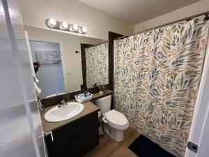 a bathroom with a shower with a toilet and a sink at 3 Adjacent 4-bed Homes - Park Views, Fully Stocked in Grande Prairie +26 photos