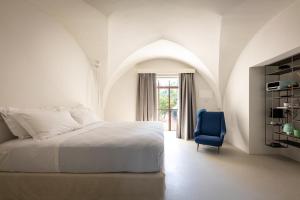 een slaapkamer met een bed en een blauwe stoel bij Palazzo Villani Lubelli in Cannole +83 foto's