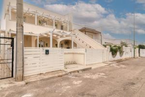 een wit huis met een hek en een hek bij Appartamento Corallo in Porto Cesareo