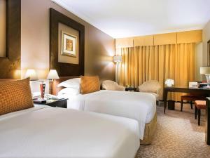 a hotel room with two beds and a desk at Swissôtel Al Murooj Dubai in Dubai