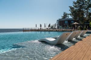 a pool with a row of white chairs in the water at Ліс&More in Glebovka