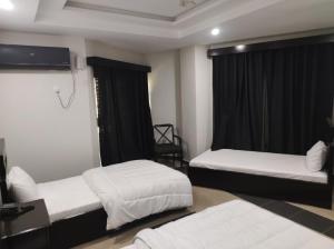 a hotel room with two beds and a television at Moon Living Apartment Peshawar in Peshawar +2 photos