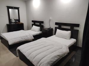 a bedroom with two beds with white sheets and a mirror at Moon Living Apartment Peshawar in Peshawar