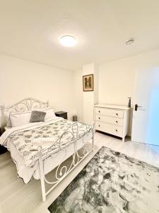 a white bedroom with a white bed and a dresser at 4 Bedroom House CheapUKholiday in Dagenham