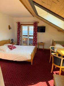 a bedroom with a bed and a table and chairs at L'Auberge au Bord du Lac in Gérardmer